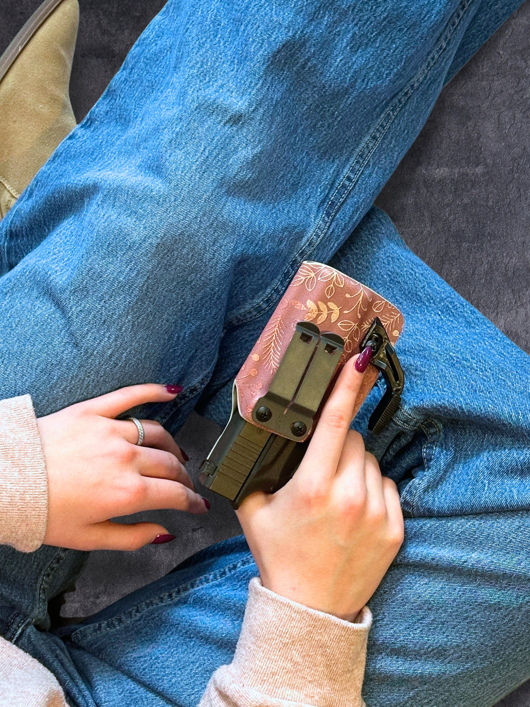 Amelia IWB concealed carry holster in Rose Gold with concealment wing, resting on a knee in jeans #color_rose-gold