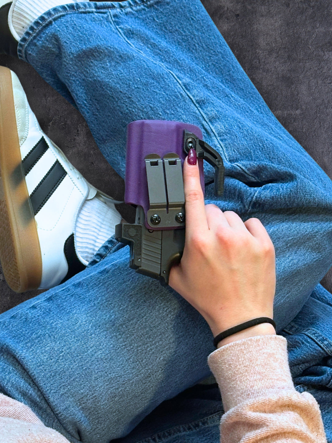 Amelia IWB concealed carry holster in Royal Purple with concealment wing, resting on a knee in jeans and sneakers #color_royal-purple