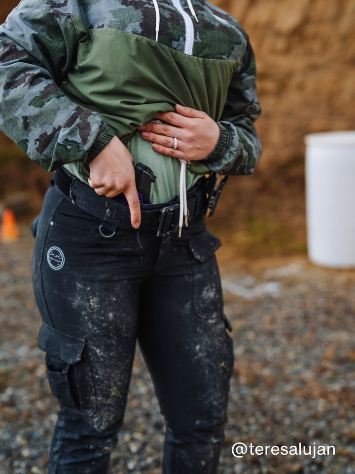 Woman lifting her jacket at the range to show the Betty 2.0 IWB holster carried appendix inside her waistband